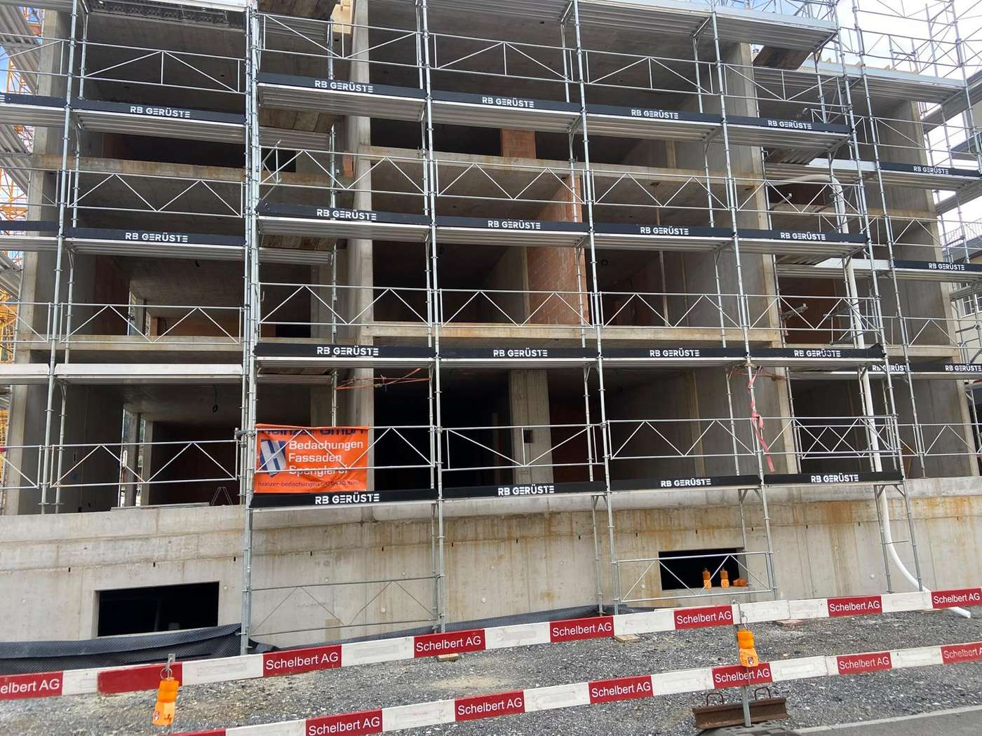 Fassadengerüst von RB Gerüste an einem Neubau im Rohbau, mit Bordbrettern «RB Gerüste» auf jeder Lage